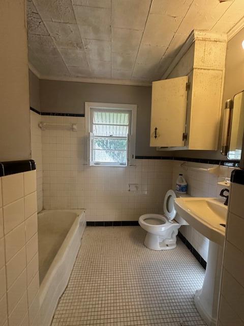 151 Lorrie St, Sardis, GA 30456 - bathroom featuring tile patterned floors, ornamental molding, tile walls, toilet, and a tub