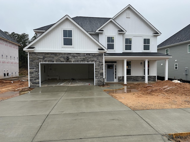 view of front facade with a porch, a shingled roof, concrete driveway, a garage, and board and batten siding