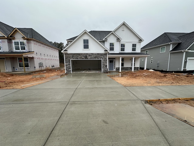 view of front facade featuring a porch, concrete driveway, an attached garage, and stone siding