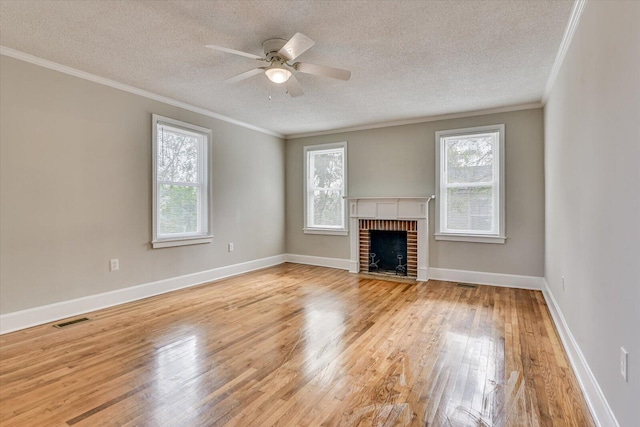 unfurnished living room featuring ornamental molding, a brick fireplace, a wealth of natural light, and light hardwood / wood-style floors