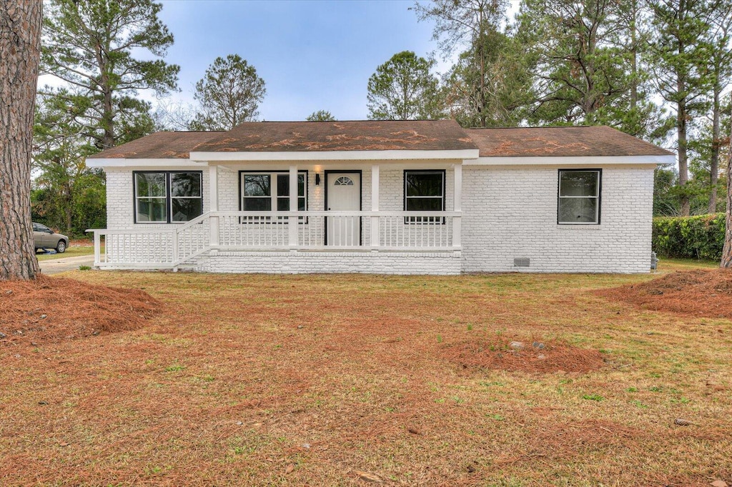 ranch-style home featuring covered porch and a front yard