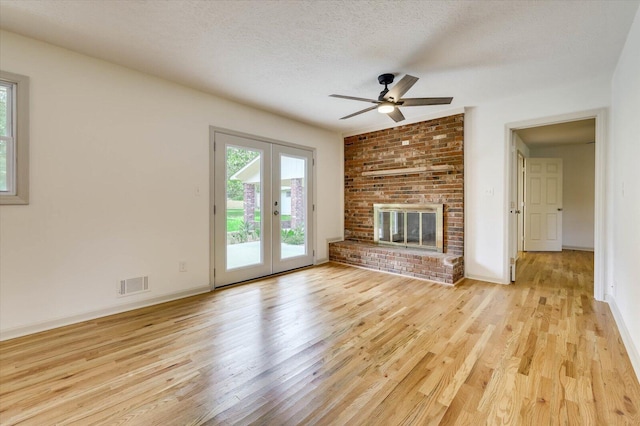 unfurnished living room featuring ceiling fan, light wood-type flooring, a textured ceiling, and french doors