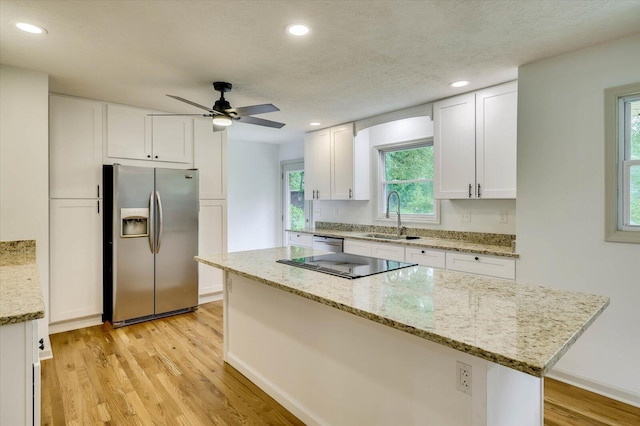 kitchen with ceiling fan, sink, stainless steel appliances, light stone counters, and white cabinets