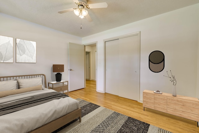 bedroom featuring a textured ceiling, a closet, light hardwood / wood-style floors, and ceiling fan