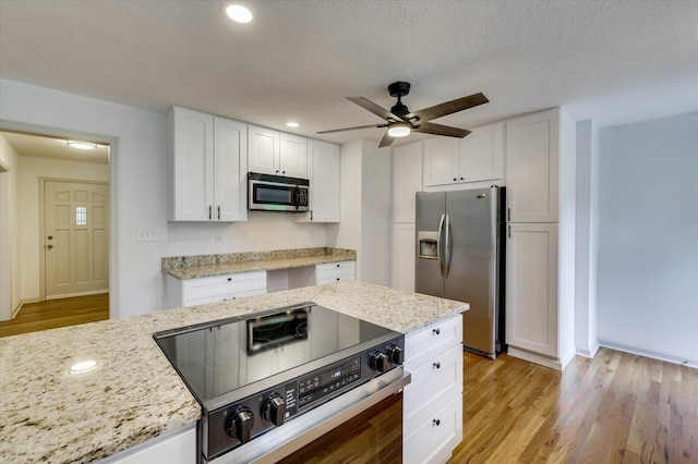 kitchen featuring white cabinetry, light stone counters, and appliances with stainless steel finishes