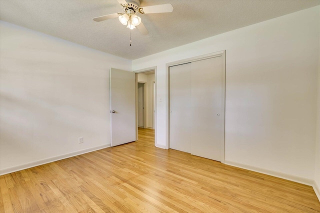 unfurnished bedroom with ceiling fan, light hardwood / wood-style floors, a textured ceiling, and a closet