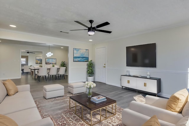 living room with ceiling fan, ornamental molding, hardwood / wood-style floors, and a textured ceiling