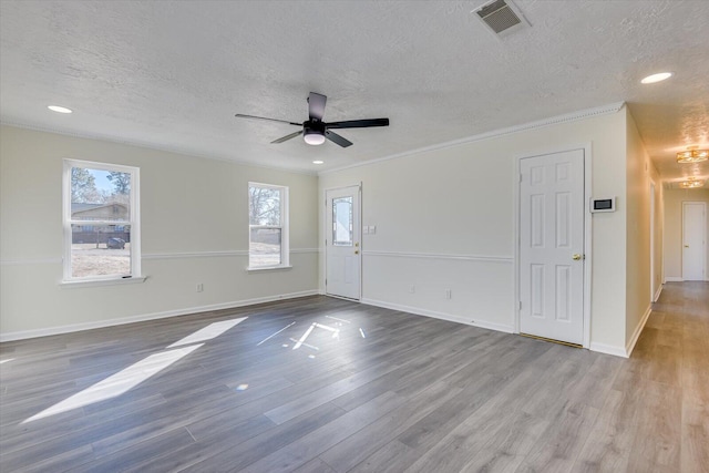 spare room with ceiling fan, ornamental molding, a textured ceiling, and light hardwood / wood-style floors