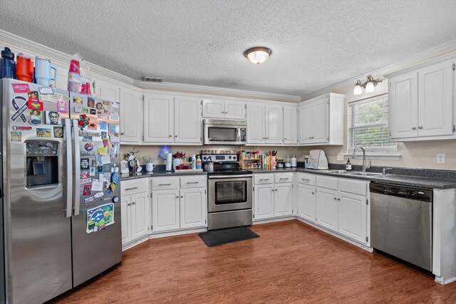 762 Winding Creek Ct, Evans, GA 30809 - kitchen featuring appliances with stainless steel finishes, dark countertops, a sink, a textured ceiling, and wood finished floors