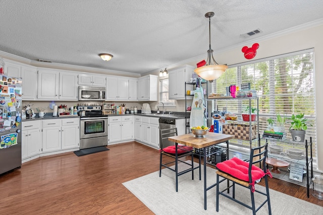 762 Winding Creek Ct, Evans, GA 30809 - kitchen featuring stainless steel appliances, dark countertops, a textured ceiling, ornamental molding, and dark wood-style flooring