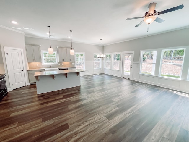kitchen with a center island, pendant lighting, light countertops, a kitchen bar, and dark wood-style floors