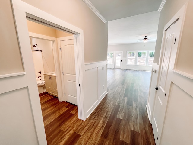 corridor with dark wood-type flooring and crown molding