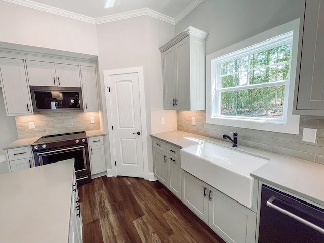 kitchen featuring a sink, backsplash, crown molding, light countertops, and appliances with stainless steel finishes