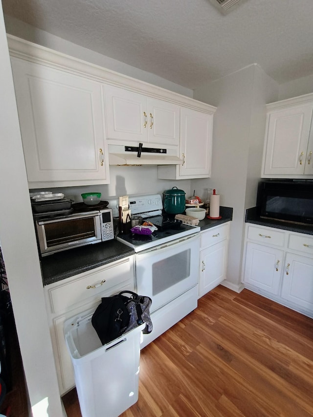 kitchen featuring dark countertops, black microwave, under cabinet range hood, white cabinets, and white electric stove