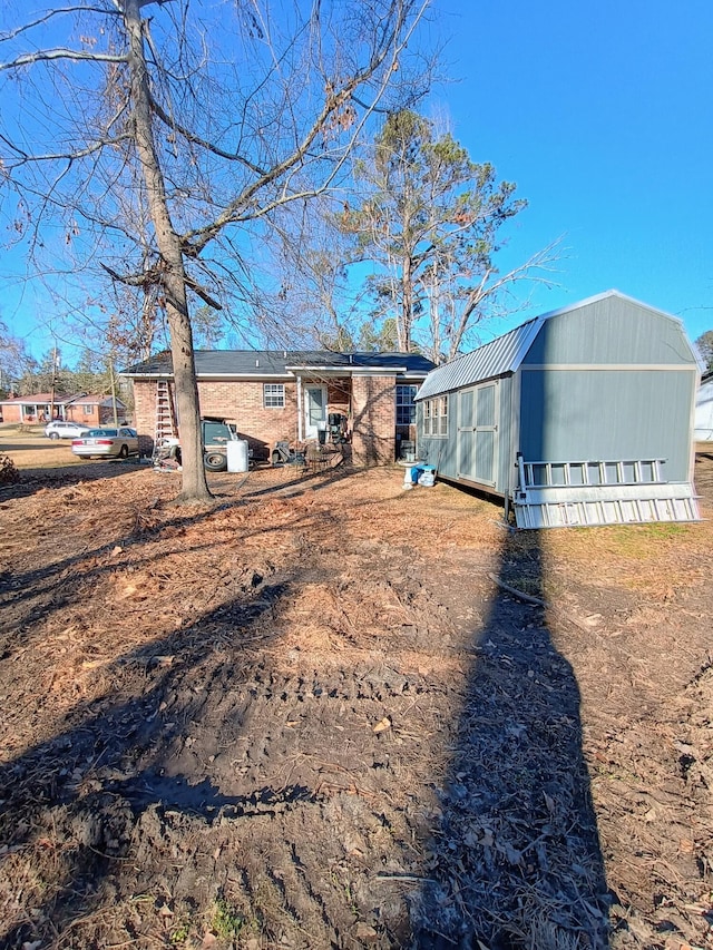 rear view of house with metal roof and an outdoor structure