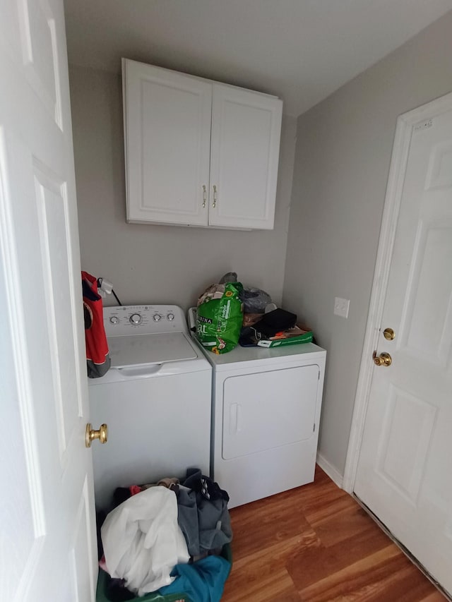 washroom with cabinet space, washing machine and dryer, and light wood-type flooring