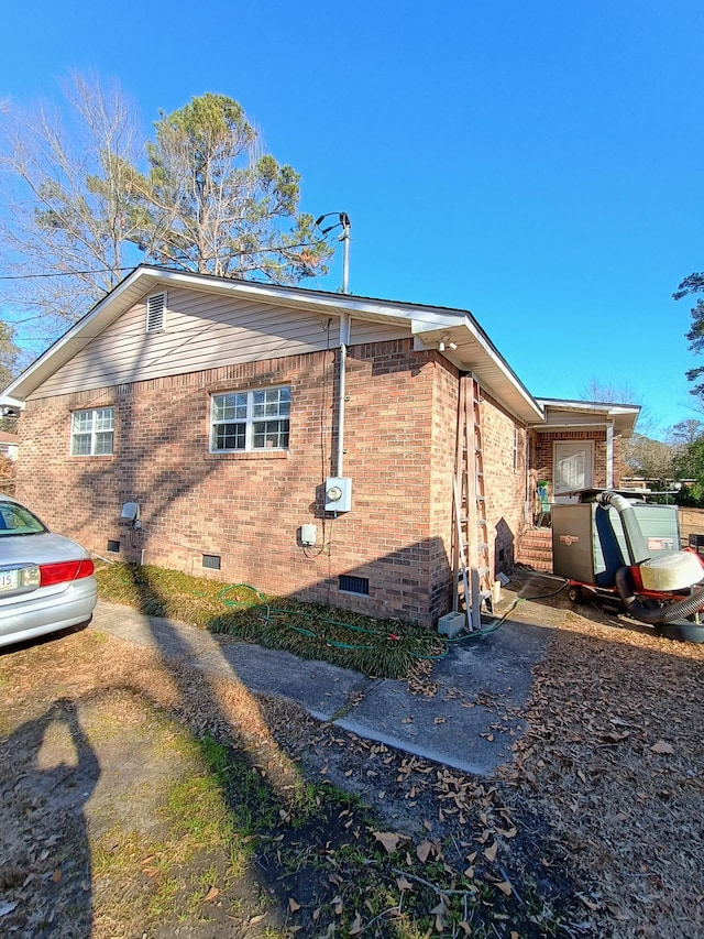 view of side of property with brick siding and crawl space