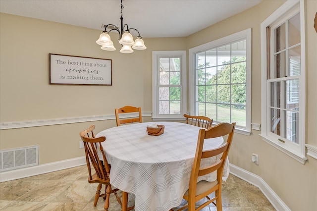 dining room featuring baseboards, stone finish floor, a chandelier, and visible vents