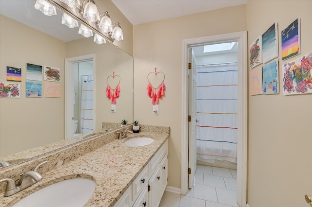 bathroom featuring double vanity, baseboards, a sink, and tile patterned flooring
