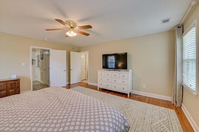 bedroom featuring baseboards, a ceiling fan, wood finished floors, and visible vents