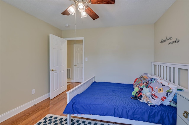 bedroom featuring baseboards, light wood-style flooring, ceiling fan, and visible vents