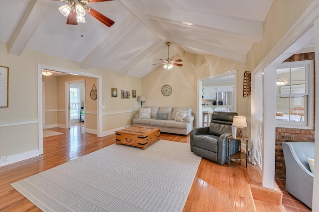 living area featuring ceiling fan, lofted ceiling with beams, baseboards, and light wood finished floors