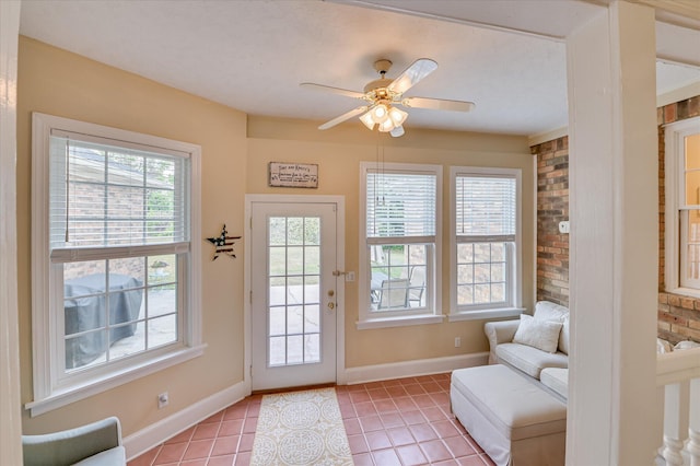 doorway to outside with baseboards, ceiling fan, and light tile patterned floors