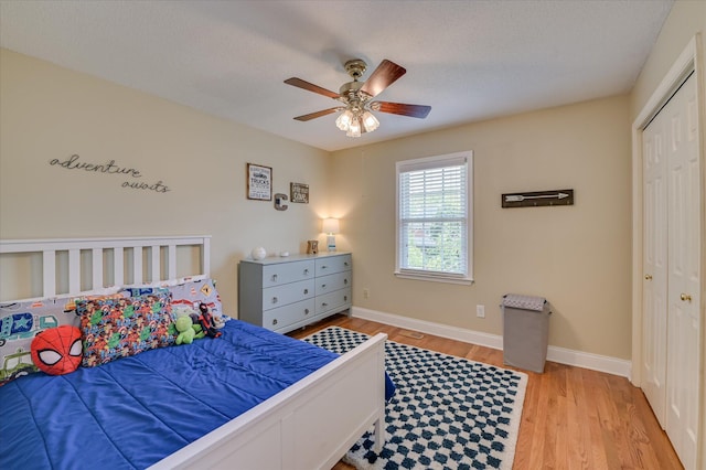 bedroom with baseboards, light wood-type flooring, ceiling fan, and a closet