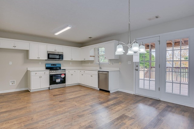 kitchen featuring white cabinetry, hanging light fixtures, stainless steel appliances, and dark hardwood / wood-style floors