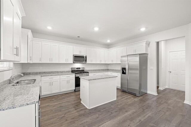 kitchen featuring white cabinetry, sink, a center island, light stone countertops, and appliances with stainless steel finishes