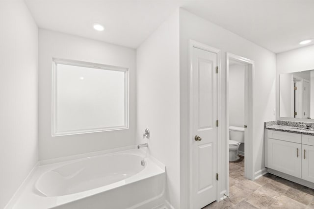 bathroom featuring vanity, toilet, and a tub