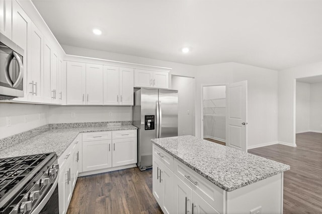 kitchen featuring white cabinetry, a center island, light stone countertops, dark hardwood / wood-style flooring, and appliances with stainless steel finishes