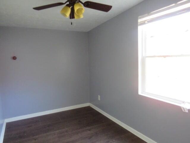 spare room featuring ceiling fan, dark wood-type flooring, and baseboards