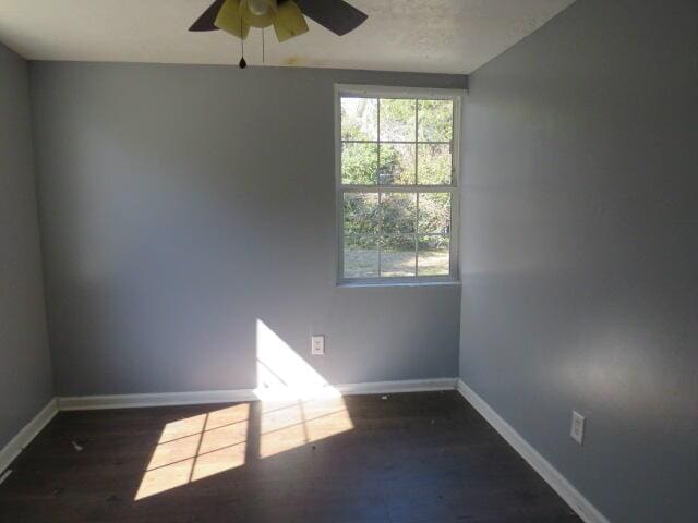 empty room featuring dark wood-style flooring, ceiling fan, and baseboards