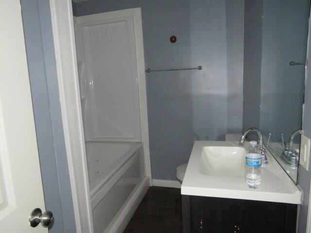 full bathroom featuring a tub, baseboards, vanity, and toilet