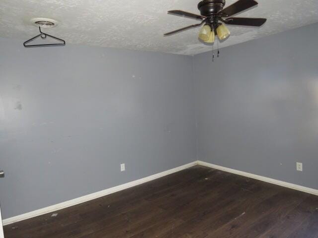 unfurnished room featuring a ceiling fan, a textured ceiling, baseboards, and dark wood-style flooring