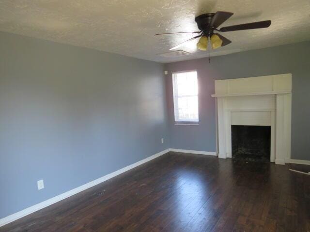 unfurnished living room with dark wood-style floors, a fireplace, baseboards, and a textured ceiling