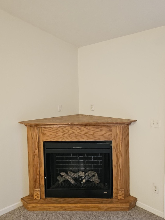 room details with carpet floors, a fireplace with raised hearth, and baseboards