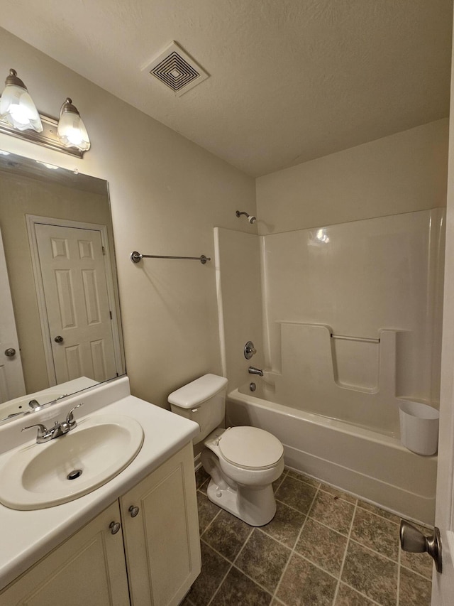 bathroom with a textured ceiling, toilet, vanity, visible vents, and washtub / shower combination