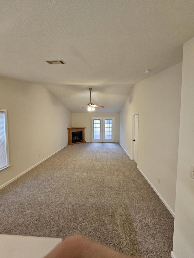 unfurnished living room with visible vents, baseboards, carpet, vaulted ceiling, and a fireplace