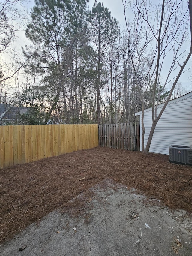 view of yard featuring central AC and fence