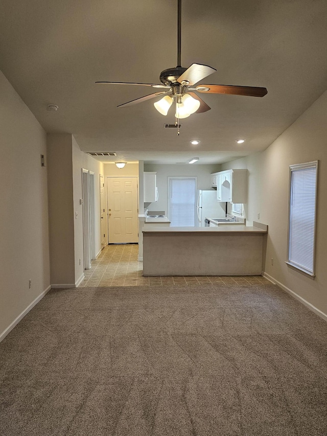 unfurnished living room with light colored carpet, ceiling fan, visible vents, and baseboards