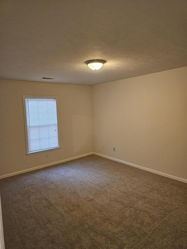 spare room featuring a textured ceiling, carpet floors, and baseboards