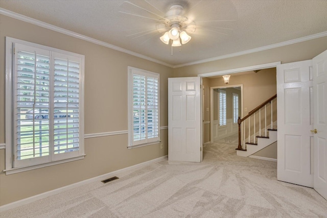 carpeted empty room featuring a textured ceiling, ceiling fan, and ornamental molding