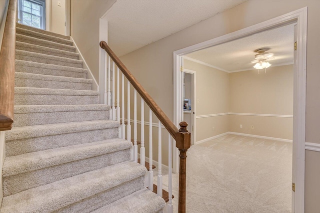 staircase with carpet flooring, a textured ceiling, and ornamental molding