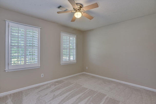 empty room featuring ceiling fan, light colored carpet, and a textured ceiling