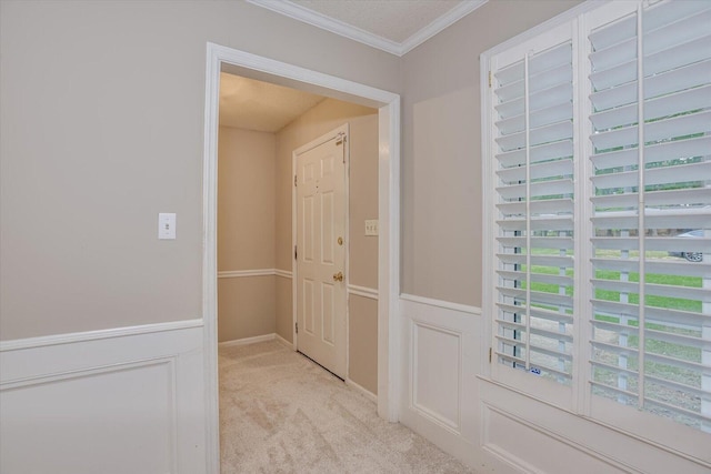 hallway with light carpet, a textured ceiling, and crown molding