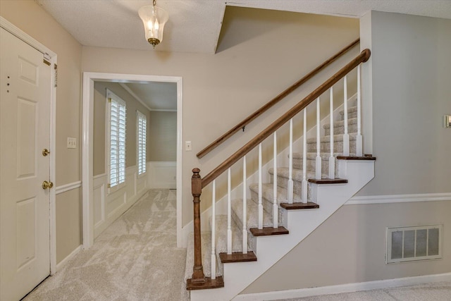 foyer with light colored carpet and a textured ceiling