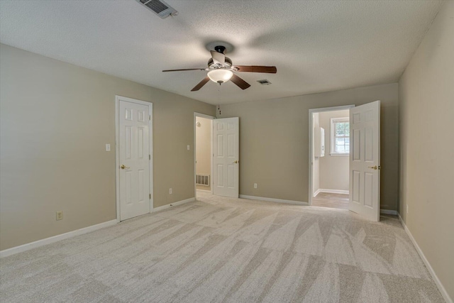 unfurnished bedroom featuring ceiling fan, light carpet, and a textured ceiling