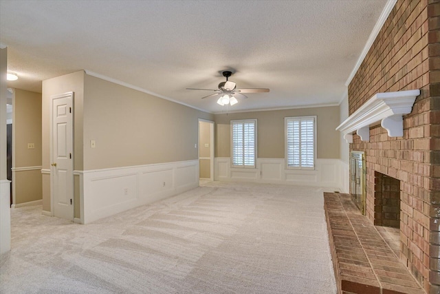 unfurnished living room featuring carpet flooring, ceiling fan, crown molding, and a brick fireplace